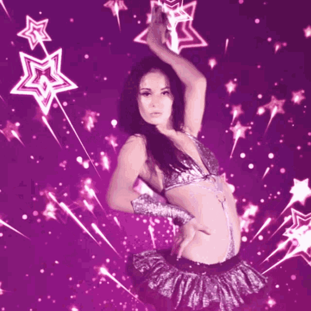 a woman is dancing in front of a purple background with stars coming out of it