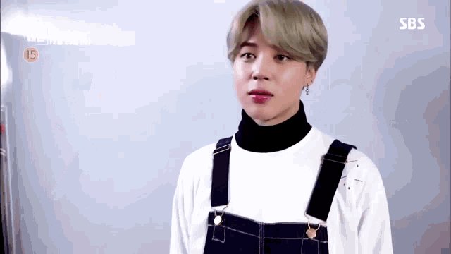 a close up of a person wearing overalls and a white shirt