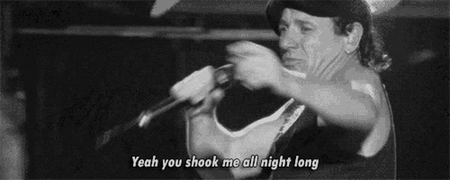a man singing into a microphone with the words yeah you shook me all night long .