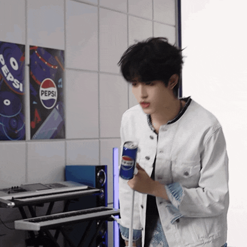 a man is holding a can of pepsi in front of a pepsi sign