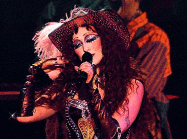 a woman is singing into a microphone while wearing a cowboy hat