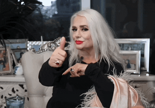 a woman with long white hair is giving a thumbs up sign