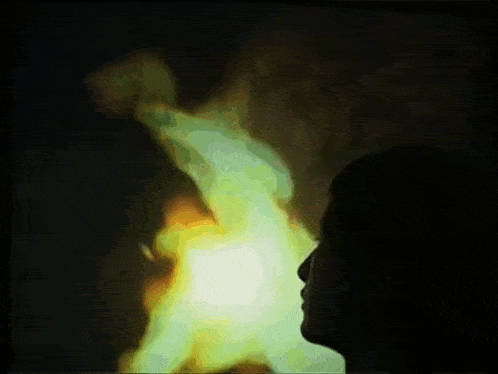 a silhouette of a person looking up at a green light