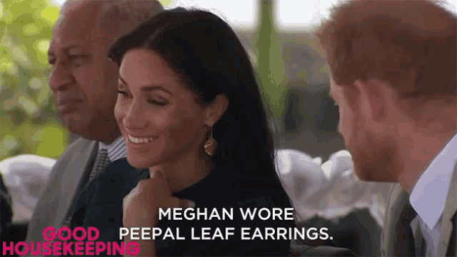 a woman wearing a pair of peepal leaf earrings smiles while sitting next to two men