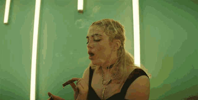 a woman smoking a cigar with a tattoo on her arm that says ' i 'm a bad girl '