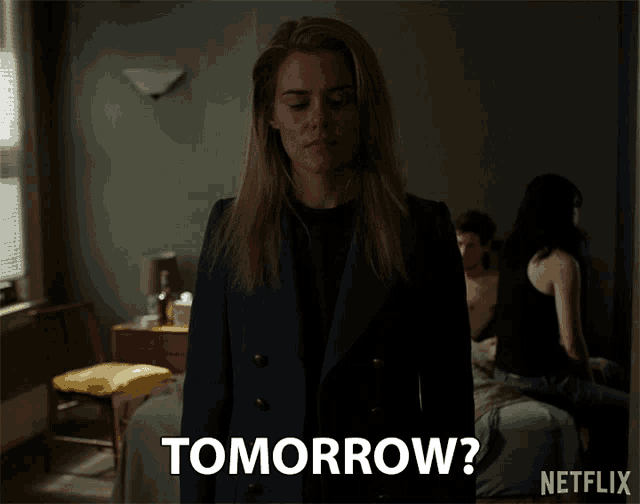 a woman standing in a dark room with tomorrow written on the bottom of her jacket