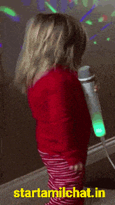 a little girl is singing into a microphone and the website startamilechat.in is visible