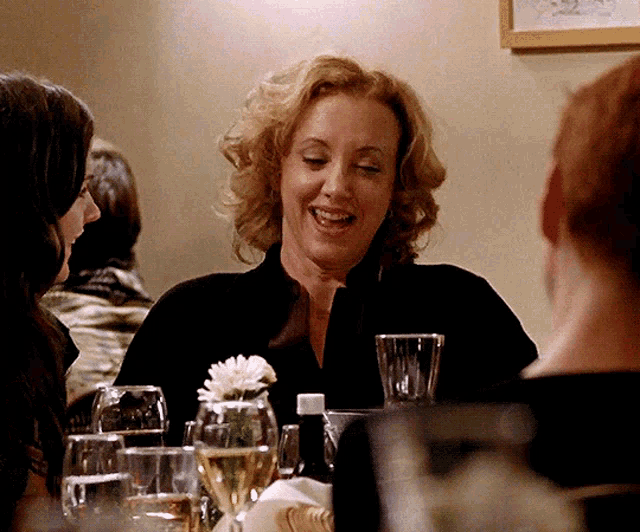 a woman is sitting at a table with glasses of wine