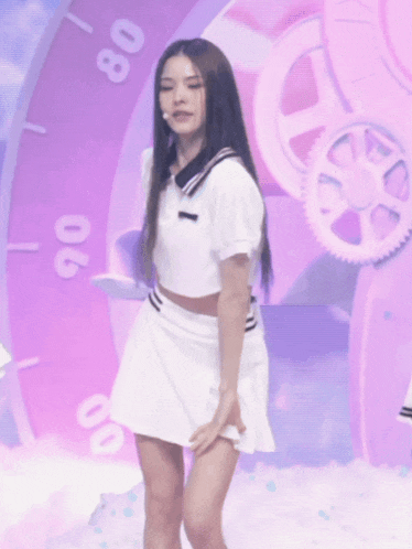 a woman in a white crop top and skirt is standing in front of a clock that says 80