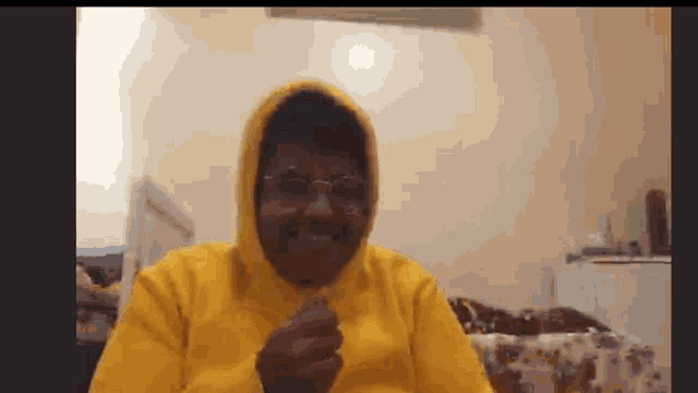 a man wearing glasses and a yellow hoodie is smiling .