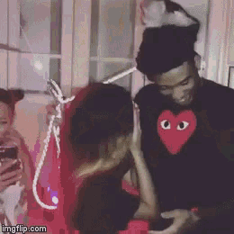 a man wearing a black shirt with a red heart on it is talking to a woman