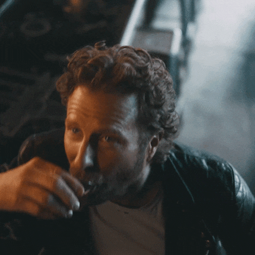 a man with a beard is drinking from a bottle