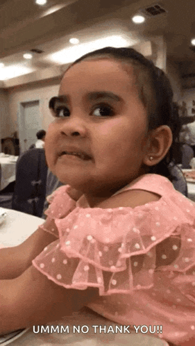 a little girl in a pink dress is making a funny face and says ummm no thank you