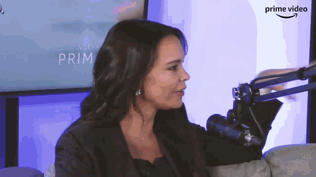 a woman sitting in front of a microphone with a sign that says prime video