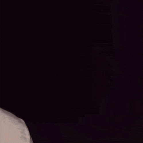 a man with a beard is looking at the camera in the dark