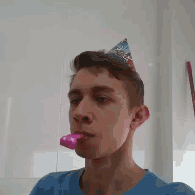 a young man wearing a party hat is blowing a pink party horn