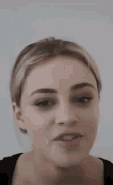 a close up of a woman 's face with a ponytail and a black shirt .