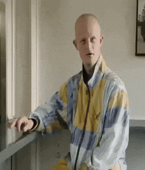 a man in a yellow and blue jacket is leaning against a wall
