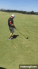 a man is swinging a golf club on a green field .