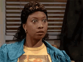 a woman with a surprised look on her face wearing a yellow shirt and a blue jacket