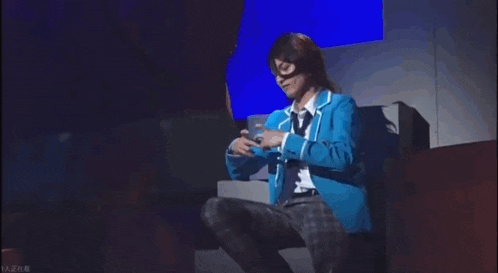 a man in a blue jacket and plaid pants is kneeling down on a stage .