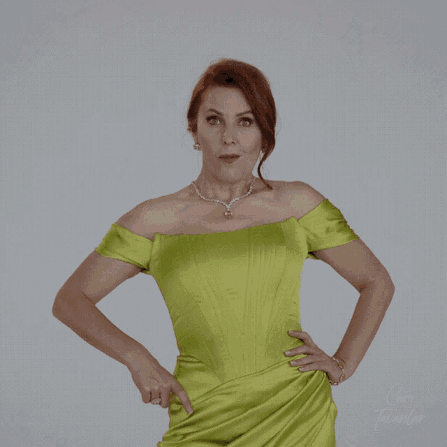 a woman in a green dress is pointing to her waist