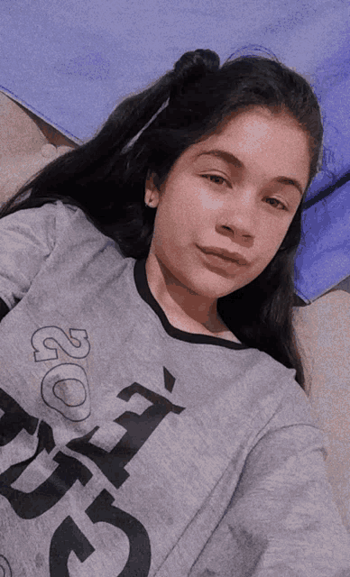 a girl wearing a grey shirt that says ' 20 ' on the front