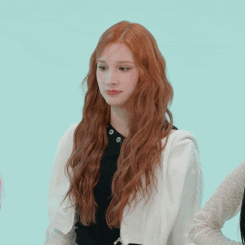a woman with long red hair is wearing a black shirt and a white jacket