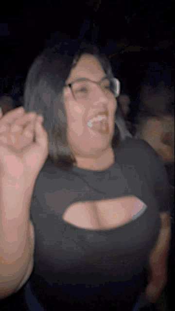 a woman with glasses and a large breast is dancing in a club .