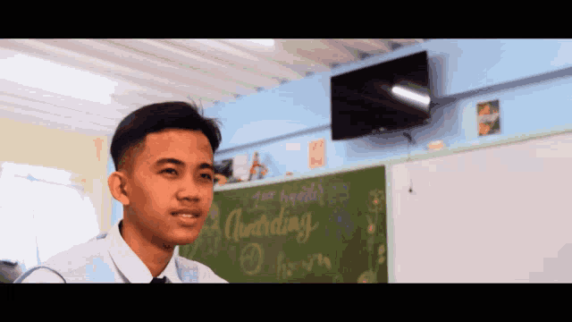 a young man stands in front of a chalkboard that says " according " on it
