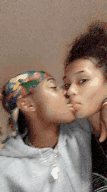 two girls are kissing each other on the cheek .