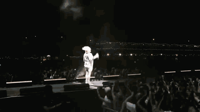 a blurry picture of a man in a white shirt standing in the dark .