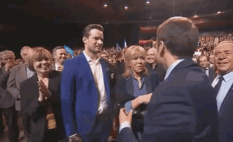 a man in a blue suit is kissing a woman in front of a crowd