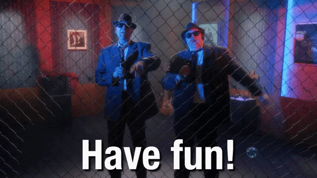 two men behind a chain link fence with the words have fun written on it