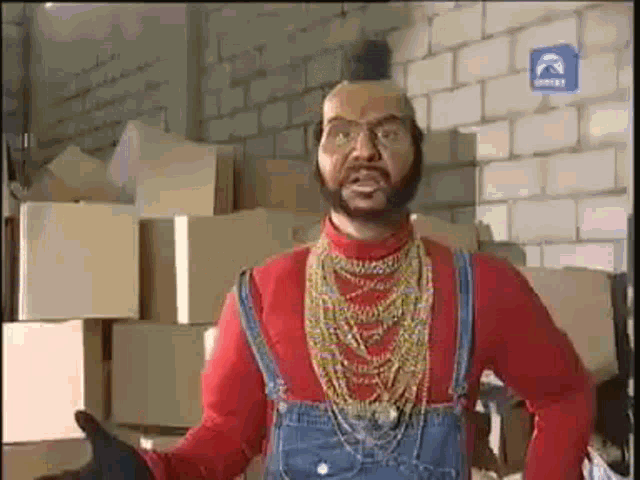 a man wearing overalls and a red shirt is standing in front of a pile of cardboard boxes .