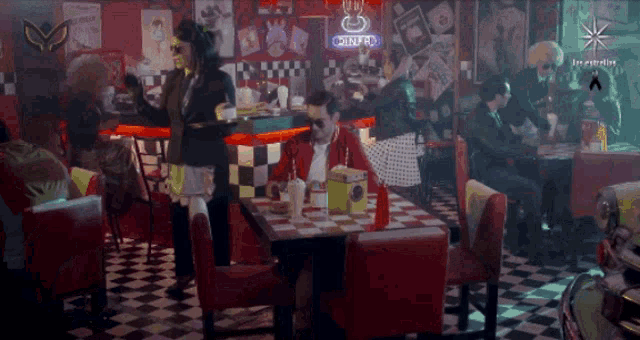 people sitting at tables in a diner with a neon sign that says ' cafecito '