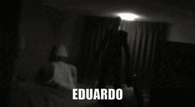 a man in a suit is standing in a dark room and the name eduardo is on the bottom right