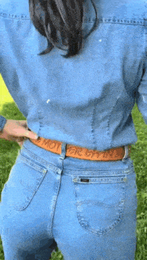 a woman wearing a denim shirt and jeans has a belt that says mother lying