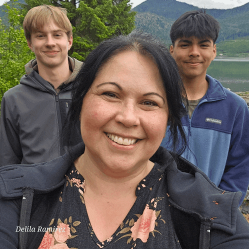 a woman wearing a columbia jacket smiles with two boys in the background