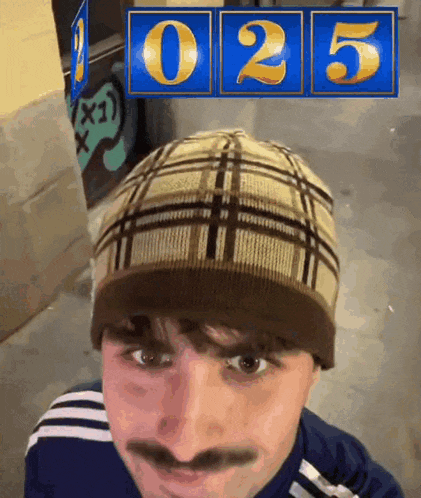 a man wearing a plaid hat stands in front of a sign that says 025