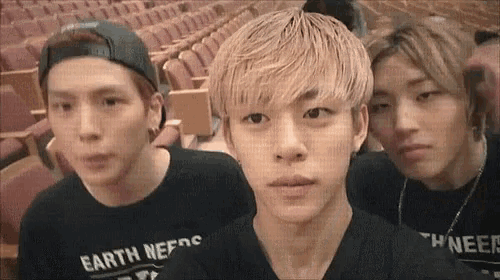 three young men are standing next to each other in an auditorium wearing shirts that say earth needs