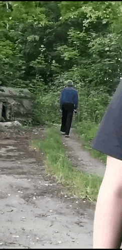 a man in a hat is walking down a dirt path