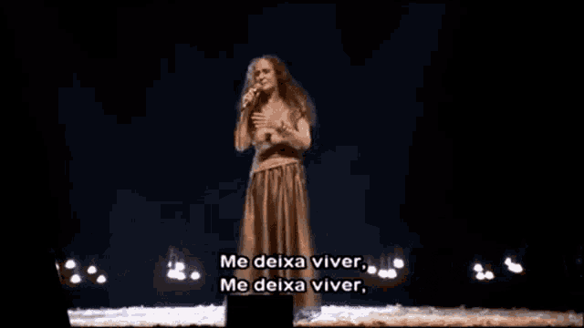 a woman is singing into a microphone on stage .