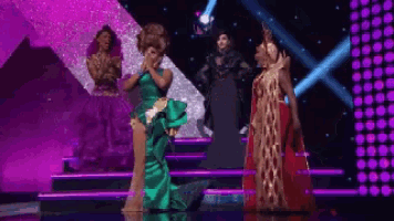 a woman in a green dress is kneeling on a stage