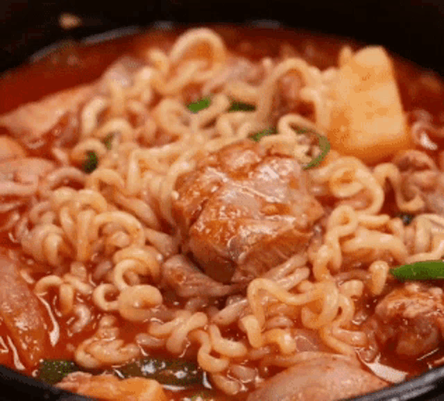 a bowl of noodles with meat and vegetables in a sauce