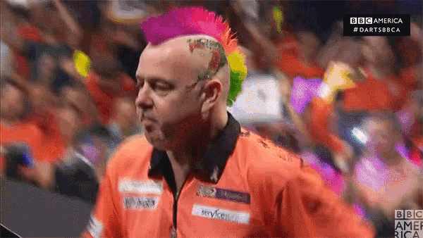 a man with a colorful mohawk stands in front of a crowd of people