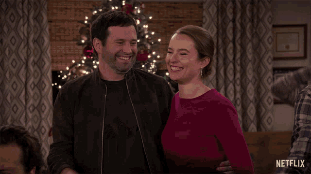 a man and woman are hugging in front of a christmas tree with netflix written on the bottom