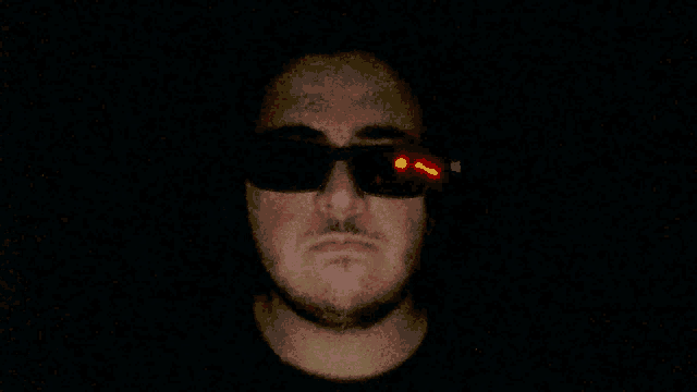 a man wearing sunglasses has a red light coming out of his eyes