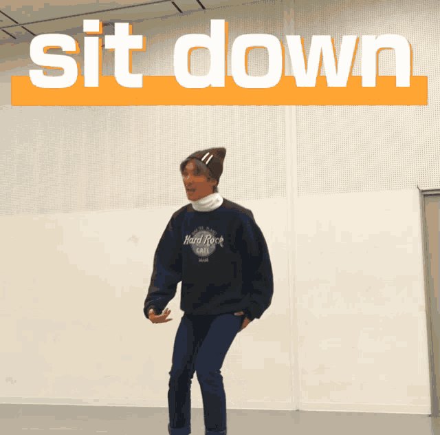 a man wearing a hard rock cafe sweatshirt is squatting