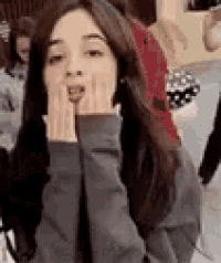 a woman with long hair is making a funny face with her hands over her mouth .